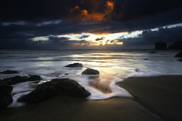 The rays of the sun on the background of the dark sky and the sea