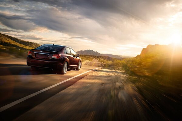 Subaru rushes along the highway at sunset