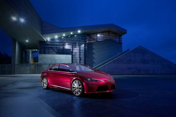 Bright red car on the background of a house at night