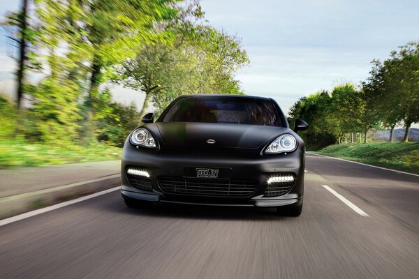 A black car is driving on an asphalt road