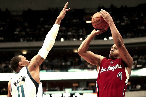 Two adult men play basketball