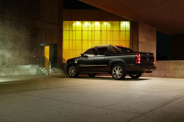 A black car is parked to the stairs near the yellow windows