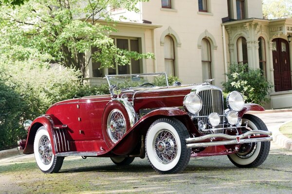 Red retro car on the background of a mansion