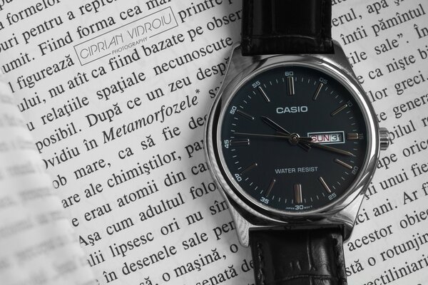 A watch with a black dial is lying on a book