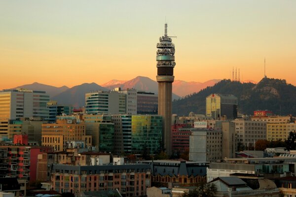 A city with a tower in the center and mountains in the background