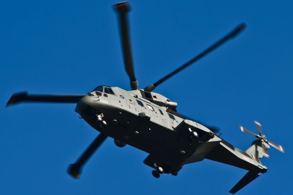 A military helicopter is flying through the sky