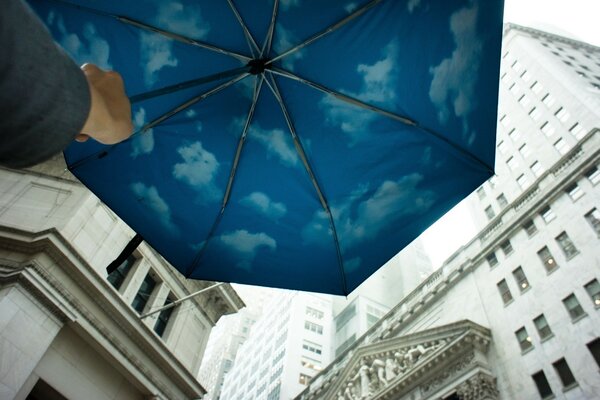 Blue umbrella with clouds near big houses