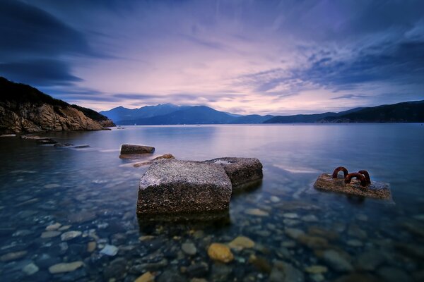 There are boulders and rocks in the water near the beach