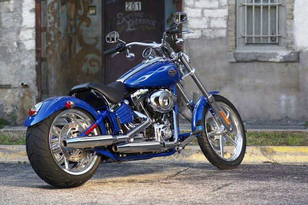 A blue motorcycle is standing in the yard of the house
