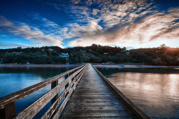 Wooden bridge across the river at sunset