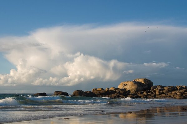 Waves on a sandy beach against a background of clouds