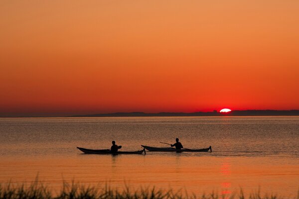 People swim on boats during sunset