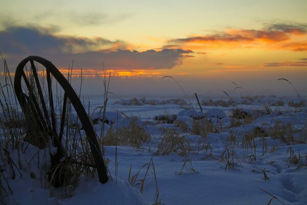 Winter sunset. The watermill is frozen in the water